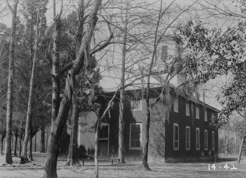 Black-and-white 1934 photo: the brick church seen from the rear through bare trees