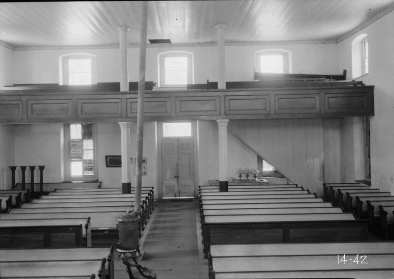 Black-and-white 1934 photo of the interior: rows of wooden pews and the gallery along the far wall