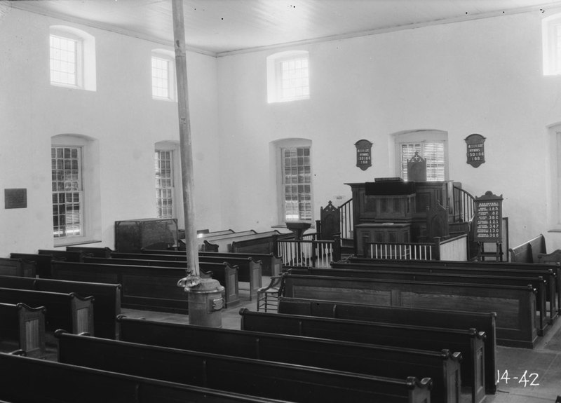 Black-and-white 1934 photo of the interior: wooden pews facing a raised pulpit between tall windows